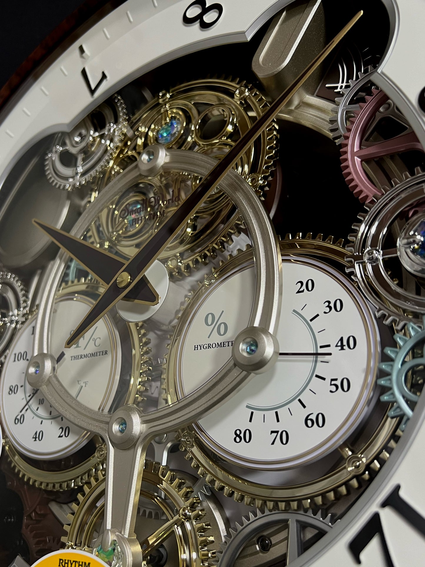 Rhythm “Widget (Woodgrain)” Skeletonized Dial Magic Motion Musical Wall Clock with Moving Gears - 4MH886WU23